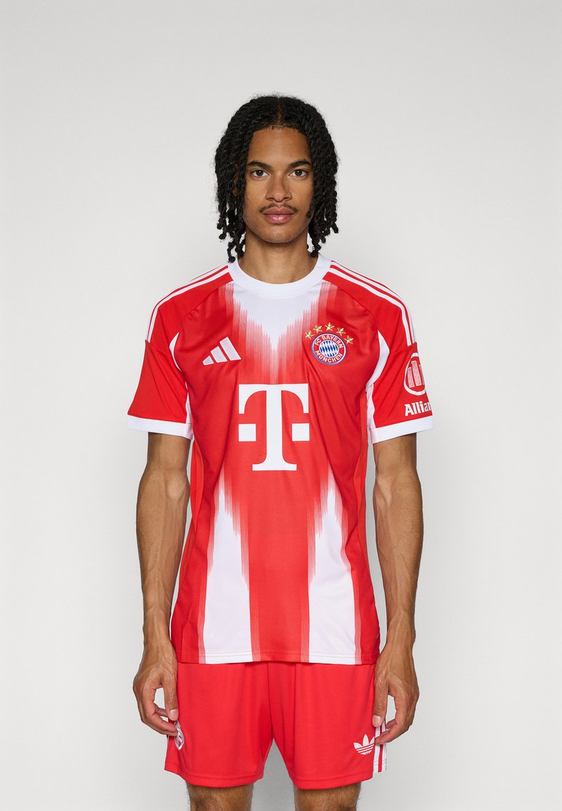 Maillot de football rouge et blanc avec des rayures verticales, présentant un logo sur la poitrine, un graphique en forme de T et des manches courtes. Assorti à un short rouge.