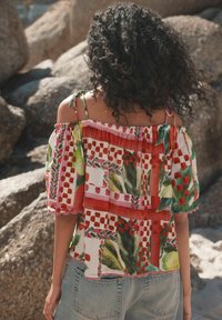Top holgado, sin hombros, con patrones florales y de cuadros coloridos. Hecho de tela liviana, con bordes con volantes y tirantes de lazo.