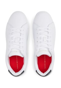 Λευκά αθλητικά παπούτσια με λείο συνθετικό επάνω μέρος, κλείσιμο με κορδόνια, κόκκινα εσώρουχα και λογότυπο "Tommy Hilfiger" σε χρυσό στο πλάι.