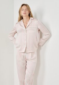 Conjunto de pijama de algodón que presenta una camisa de botones y pantalones con cintura elástica, ambos con rayas verticales alternas en rosa y blanco.