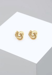 Cercei din metal auriu cu un design spiralat, având bucle intertwinate. Textură netedă și finisaj lustruit, pe un fundal neutru.