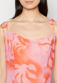 Vestido sem mangas em gradiente de rosa e laranja com padrão floral. Apresenta laços delicados nos ombros e um decote suavemente recortado.