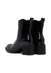 Botas de tobillo de charol negro con puntera redondeada, tacón cuadrado y cremalleras laterales que presentan una superficie lisa y brillante, además de lengüetas de tirón.