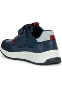 Sneaker blu navy con materiali in pelle e tessuto. Cinghie in velcro, accenti a righe rosse e bianche, e suola bianca con grip testurizzato.