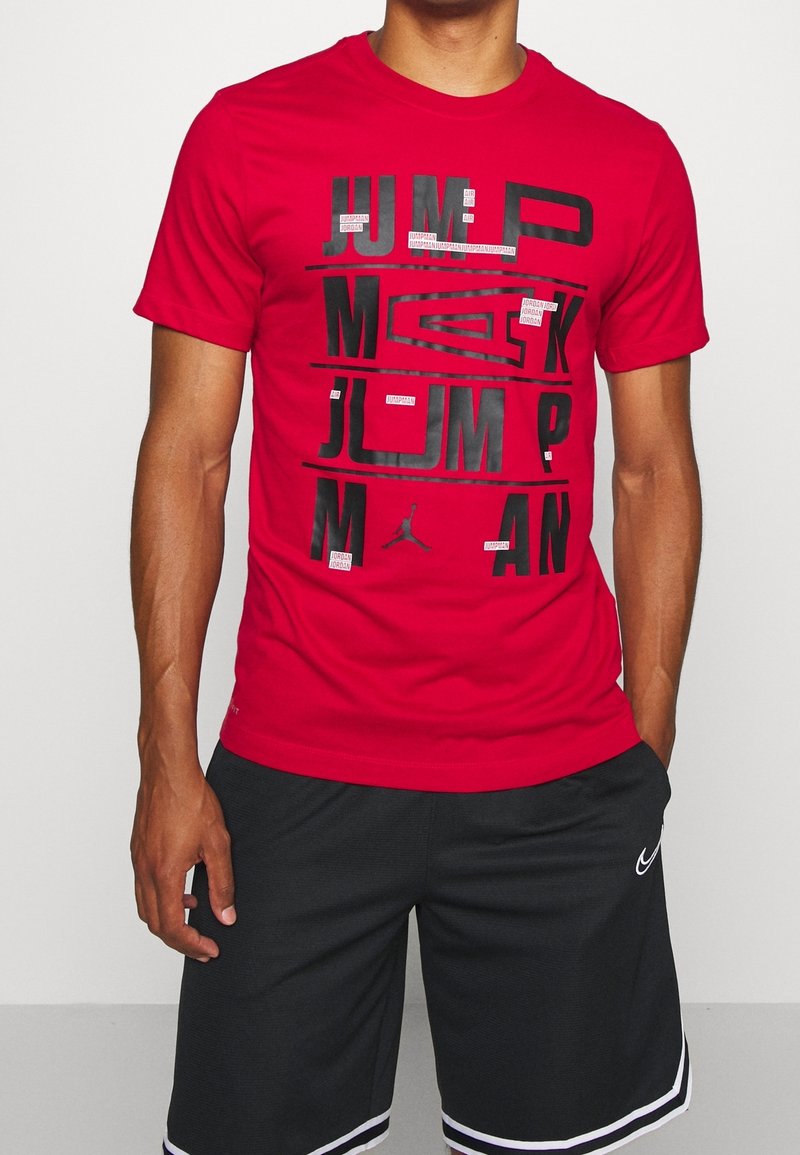 Rode katoenen t-shirt met gedurfde zwarte tekst en "Jumpman" afbeelding. Korte mouwen en ronde halsstijl. Gecombineerd met zwarte shorts.