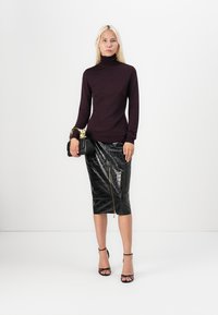 Burgundy fitted turtleneck sweater with a textured pattern paired with a black crocodile-embossed pencil skirt featuring a gold zipper detail.