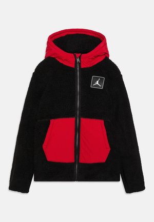Zwarte fleece jas met rits, rode capuchon en voorzakken, met een klein wit Jumpman-logo op de borst.