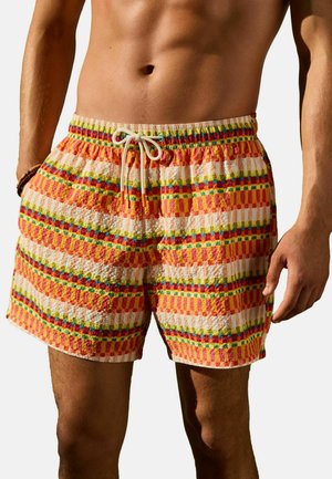 Man wearing textured swim shorts with multicolored horizontal striped pattern and a white drawstring at the waistband.