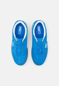 Blaue Wildledersneaker verfügen über ein Schnürdesign, weiße Akzente am Kragen und eine braune Gummisohle für besseren Halt. PUMA-Branding sichtbar.