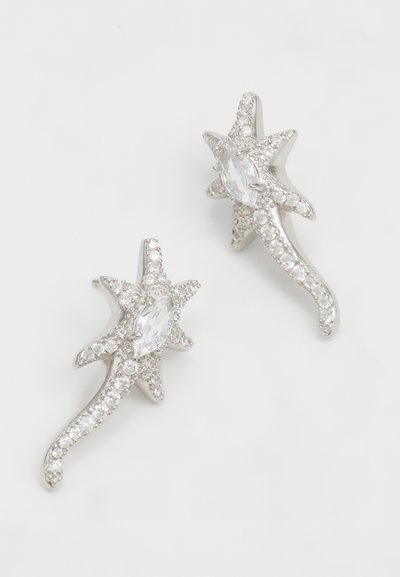 Sidabriniai auskarai su žvaigždės spindulio motyvu, centre – skaidrus akmuo, aplinkui maži cirkonio akmenėliai, tekstūruota paviršiaus detalė.