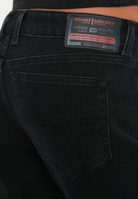 Čierne rifle z denimu s nášivkou "Diesel Industry". Výrazné prešívanie na zadných vreckách a klasický strih.