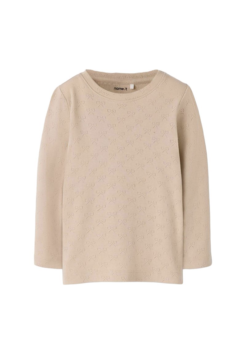Długi beżowy top z długim rękawem, ozdobiony teksturowanym wzorem drobnych serduszek. Okrągły dekolt, miękki dzianinowy materiał oraz prosty krój bez widocznych zapięć.