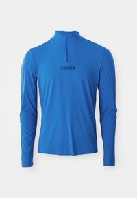 Hosszú ujjú, negyed cipzáras felső élénk kék színben, sima textúrával és a "CALVIN KLEIN" felirattal fekete színben az elülső részen.
