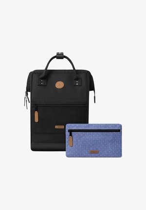 Musta kangaskassi, jossa on yläkahva, vetoketjulliset taskut ja sininen pistekuvioinen pussi vetoketjulla. Mukana nahkaosuudet ja logotyyli.