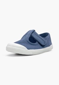 Chaussure en toile bleue pour enfant avec semelle et embout en caoutchouc blanc, fermeture velcro sur fond blanc.