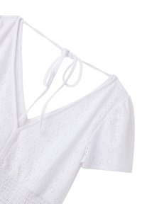 Abito bianco con maniche a sbuffo corte, caratterizzato da un motivo a pois, scollo a V profondo e lacci sulla schiena. Tessuto testurizzato con vita arricciata.