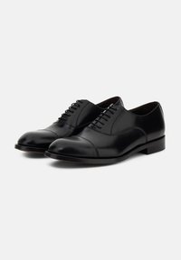 Scarpe oxford in pelle nera con finitura liscia, punta arrotondata e cinque coppie di occhielli per i lacci; con tacco basso a blocco.