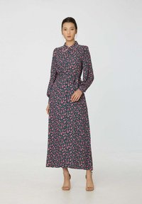 Robe à manches longues de couleur bleu marine avec un motif floral rose et un col à revers. Elle présente une taille cintrée et une jupe fluide. Tissu léger.