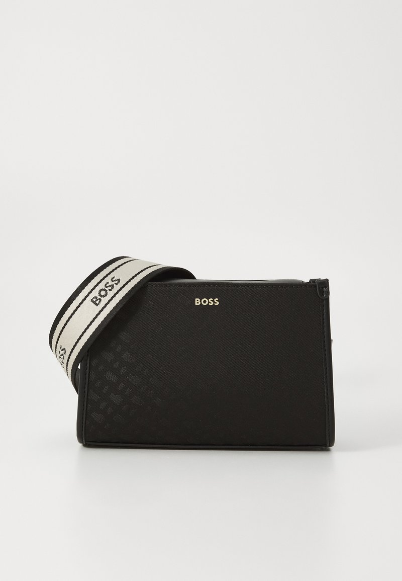 Borsa rettangolare nera in materiale testurizzato con logo dorato. Presenta una tracolla bianca a contrasto con scritte nere. Chiusura con zip.