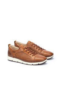 Zapatos de cuero marrón con un diseño perforado texturizado, con cordones marrones y una suela de goma blanca para contraste. Acabado suave y perfil bajo.