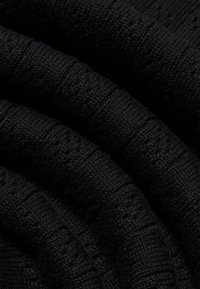 Tissu tricoté noir avec un ribbage texturé, mettant en valeur une apparence douce et flexible. Aucun motif ou détail de quincaillerie visible.