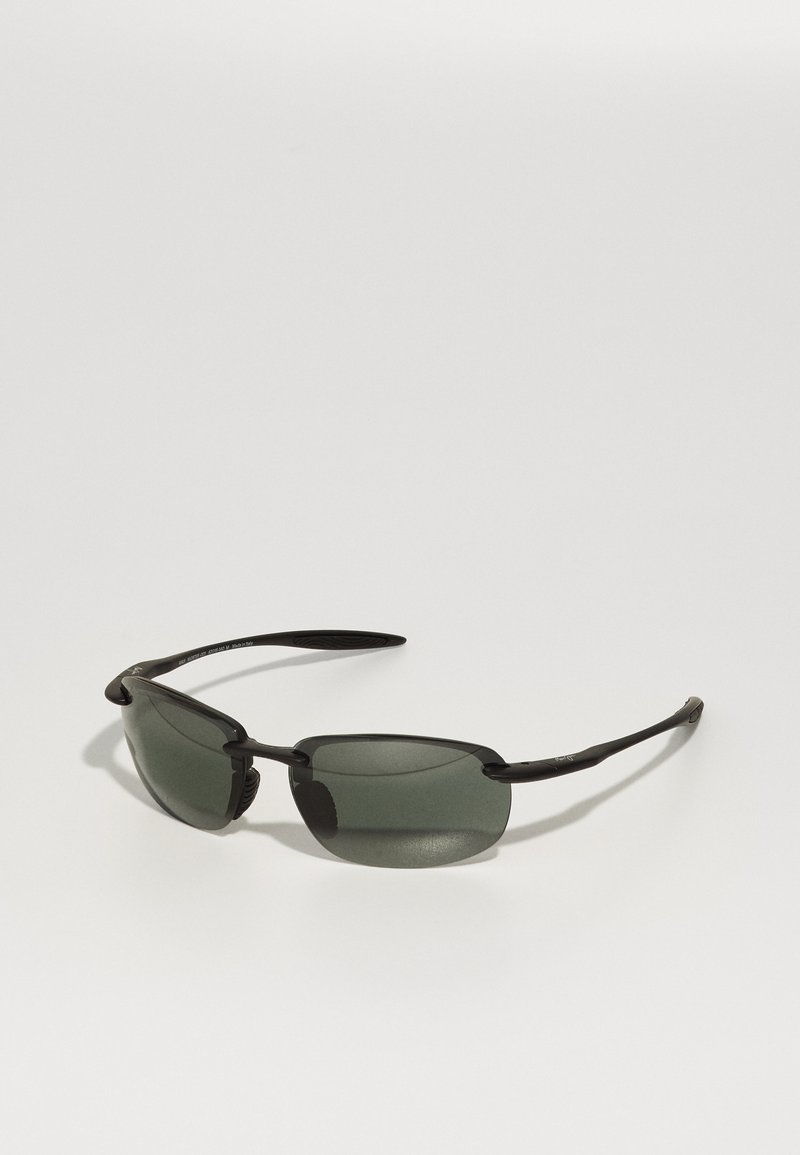 Black sunglasses with green tinted lenses, a sleek rectangular shape, and a lightweight frame design. Textured details on the temples.