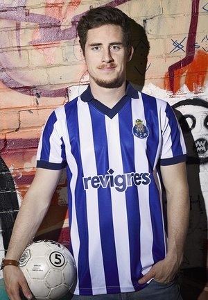 Blauw-wit verticaal gestreepte voetbalshirt met korte mouwen, v-hals en logo. Speler houdt een witte voetbal met zwarte accenten vast.