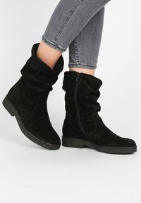 Černé semišové kotníkové boty s volným designem, vybavené bočním zipem, texturovaným svrškem a gumovou podrážkou pro lepší grip.