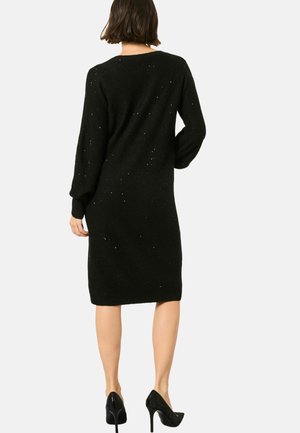 Schwarzes Strickkleid mit langenÄrmeln und rundem Ausschnitt, mit einer strukturierten Oberfläche, die kleine verstreute funkelnde Akzente aufweist.