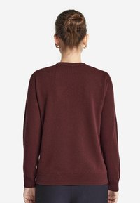 Bordeauxfarbener Pullover mit Rundhalsausschnitt, langen Ärmeln und geripptem Saum. Weiche Textur mit glatter Oberfläche und minimalistischem Design.