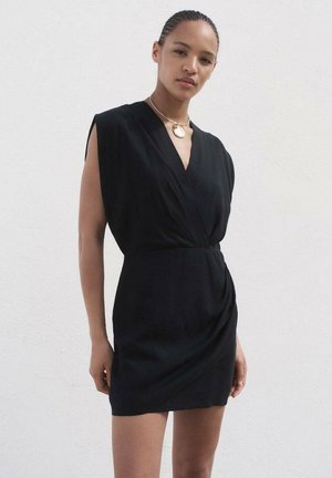 Black sleeveless dress with a deep V-neck, fitted waist, and draped detailing on the side. Smooth, lightweight fabric. Simple neckline accent.