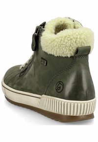 Bottine en cuir vert avec col en fourrure, zip sur le côté et semelle en caoutchouc contrastante. Finition texturée avec détail de logo sur le talon.