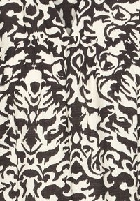 Tessuto a motivi bianco e nero con un audace design floreale astratto. La texture sembra leggermente tessuta, aumentando la profondità visiva.