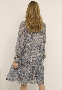 Kwiatowa sukienka midi z długimi rękawami, niebieska baza i wielokolorowy wzór kwiatowy. Posiada tiered spódnicę i luźny krój. Lekki materiał.