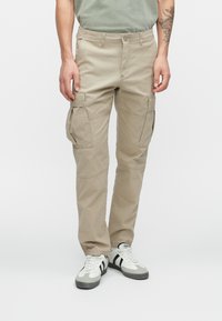 Pantalones cargo beige con múltiples bolsillos, hechos de tejido duradero. Presentan un diseño de pierna recta y costuras reforzadas para mayor resistencia.