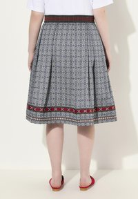 Jupe grise à motif avec une taille brodée rouge et noire, un design évasé et un ourlet avec des finitions décoratives.