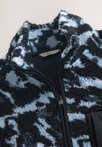 Fleecejack zwart met blauw abstract patroon, voorzien van een opstaande kraag, ritssluiting en gestructureerde stof.