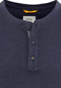 Marineblaues Henley-Shirt aus strukturiertem Stoff, mit einer Knopfleiste mit drei Knöpfen und einem kontrastierenden gelben Etikett am Kragen.