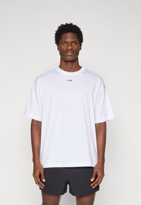 Λευκό t-shirt με κοντά μανίκια και στρογγυλή λαιμόκοψη, με εκτυπωμένο μαύρο λογότυπο "ICIW", συνδυασμένο με μαύρο σορτς. Απλός, χαλαρός σχεδιασμός.