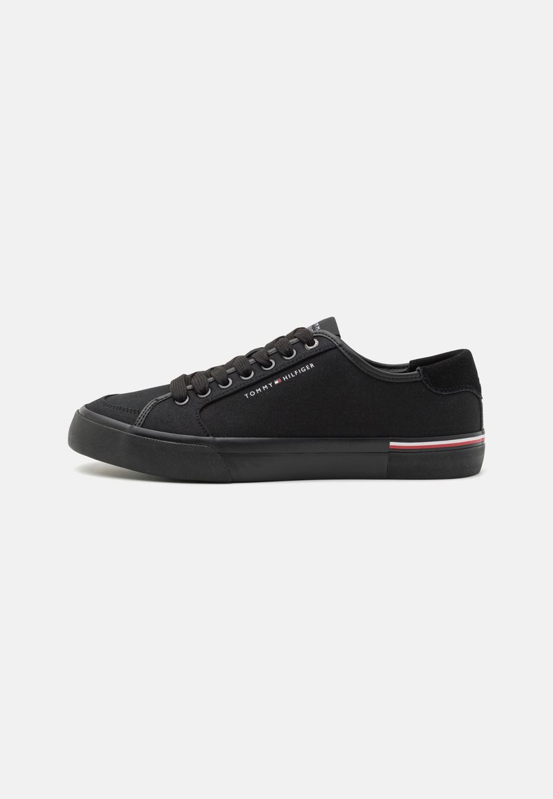 Baskets basses noires avec lacets noirs, semelle noire, petit logo Tommy Hilfiger sur le côté et bande rouge, blanche et bleue sur le talon.
