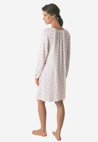 Camicia da notte bianca leggera con motivo floreale, maniche lunghe e dettaglio con yoke sul retro. Presenta una vestibilità comoda e un design fino al ginocchio.