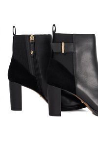 Black ankle boots featuring a combination of leather and suede, gold zipper detail, block heel, and a sleek, structured design.