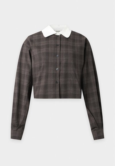 Veste courte marron à carreaux avec manches longues, boutons noirs et col pointu blanc contrastant sur fond uni.