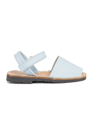 Sandal de cuero azul claro que presenta la puntera abierta, correa ajustable y suela texturada marrón. Diseño minimalista con tacón plano.