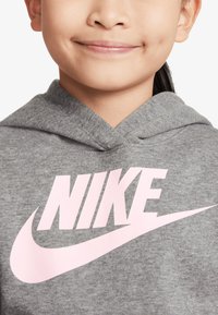 Grå hettegenser med en stor rosa "NIKE" logo på forsiden, med klassisk design og myk, teksturert stoff.