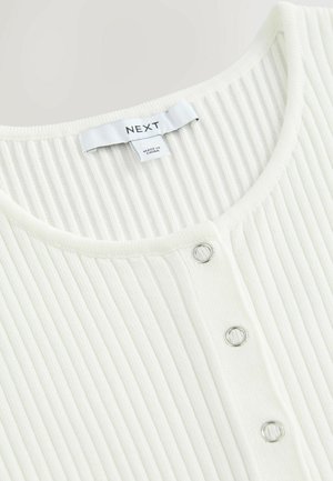 Biała bluzka prążkowana z głębokim dekoltem, z trzema srebrnymi zatrzaskami z przodu oraz metką z napisem "NEXT". Wykonana z miękkiego materiału.