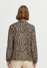 Leopardenmuster-Bluse in Braun, Beige und Schwarz; mit langen Ärmeln, einem rüschierten Ausschnitt und einer lockeren Passform. Rückansicht angezeigt.