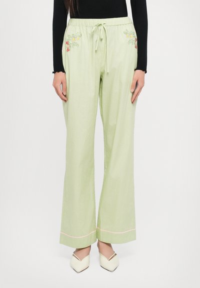 Lichtgroene wijde broek met een elastische tailleband, trekkoord en bloemenborduursel op de zakken. Roze accent aan de zoom.