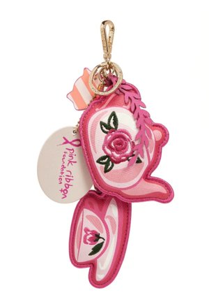 Llavero en forma de tetera y taza de té rosa con diseños florales bordados, acento de hoja rosa, cierre dorado y etiqueta de la Fundación Pink Ribbon.