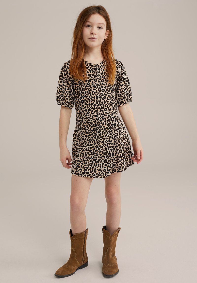 Haljina s uzorkom leoparda koja ima kratke napuhane rukave, strukirani gornji dio i lepršavu suknju. Nosila se s smeškim suedenim kaubojskim čizmama.